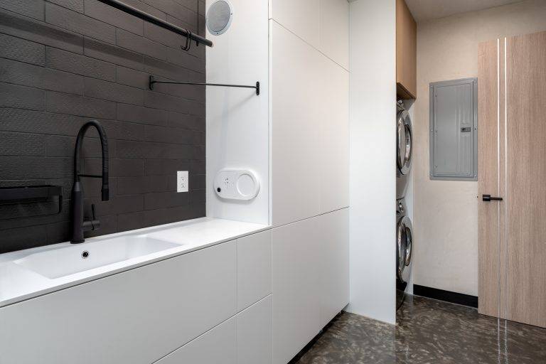 The home features a vacuum-powered laundry chute with a motion-activated port built into the wall, shown below the towel rack above, that transports dirty clothes or towels down to the first floor laundry room and then shoots them back up to the second floor, when clean. Photo by Boaz Meri courtesy VRchitects.